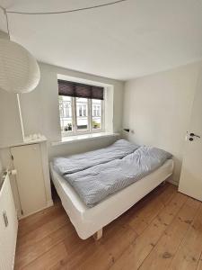a white bedroom with a bed and a window at Rebslagerhuset in Ribe