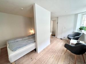 a bedroom with a bed and two chairs at Rebslagerhuset in Ribe
