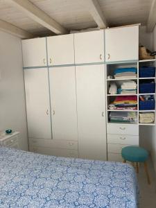 a bedroom with white cabinets and a bed and a chair at Porto Coda Cavallo in San Teodoro