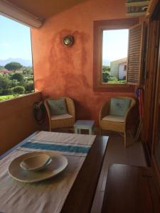サン・テオドーロにあるPorto Coda Cavalloのテーブルと椅子2脚、窓2つが備わる客室です。