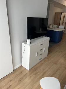 ein Wohnzimmer mit einem weißen Schrank und einem TV in der Unterkunft Marcinkowskiego 11 - 2 in Kattowitz