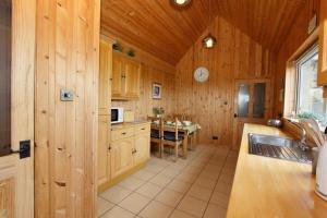 a kitchen with wooden walls and a table in it at Kelp Cottage in Pollachar