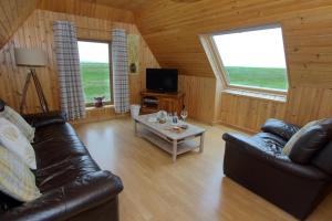Kelp Cottage في Pollachar: غرفة معيشة مع أريكة جلدية وطاولة