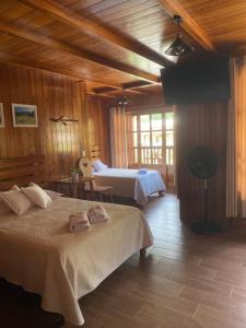 a bedroom with two beds in a room with wooden walls at HAUS KÖHEL HOSPEDAJE POZUZO in Pozuzo