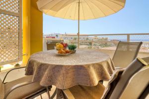 uma mesa com uma taça de fruta e um guarda-chuva em Orlando - Ocean View Apartment in Costa Adeje em Adeje