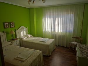 a green room with two beds and a window at Fuenteazul in Hortigüela