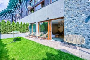 a backyard with chairs and a table and a building at Splendor 3 bedroom flat in Silver Mountain in Poiana Brasov