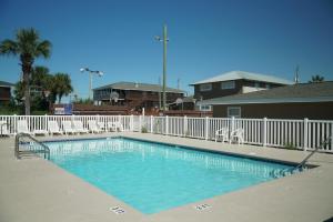a swimming pool with chairs and a white fence at Cottages Christian Retreat in Panama City Beach