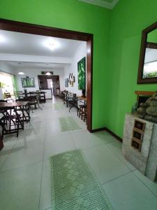 a dining room with green walls and tables and chairs at Pousada Char in Ubatuba