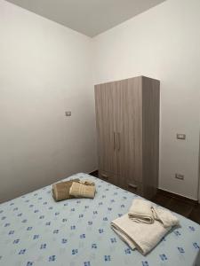 a bedroom with a bed with a cabinet and towels at La casa di Peppe in Monasterace