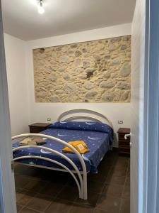 a bedroom with a bed and a stone wall at La casa di Peppe in Monasterace