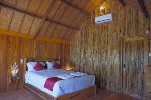 a bedroom with a bed in a room with wooden walls at The Tamban Jukung in Nusa Penida