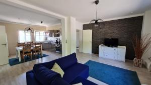 a living room with a blue couch and a kitchen at Ferienwohnung Ollywood, Natur pur im Westerwald, 2 bis 4 Personen in Halbs