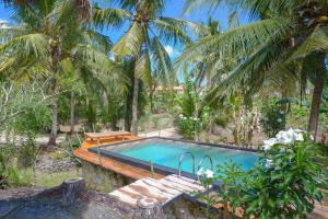 a swimming pool with a bench and palm trees at The Tamban Jukung in Nusa Penida