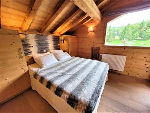 uma cama num quarto de madeira com uma janela em Chalet Les Gets, 8 pièces, 14 personnes - FR-1-598-27 em Les Gets