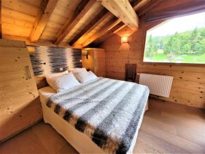 a bed in a wooden room with a window at Superbe chalet avec piscine et hammam à 50m des pistes - FR-1-598-27 in Les Gets
