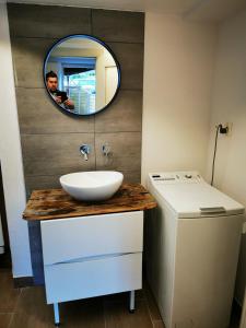 a man taking a picture of a bathroom with a sink and a mirror at Joli appartement au cœur du village in Orsières