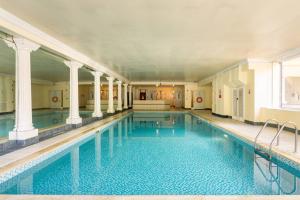 a large swimming pool with blue water in a building at Central, Bright 2 Bed Flat - Pool & Sauna in Edinburgh