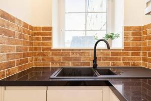 a kitchen with a sink and a brick wall at Central, Bright 2 Bed Flat in Edinburgh +17 photos
