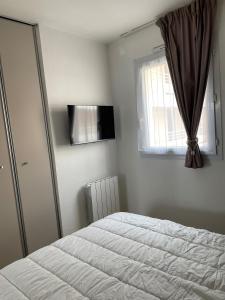 sypialnia z białym łóżkiem i oknem w obiekcie Appartement T2 de charme les minimes w La Rochelle