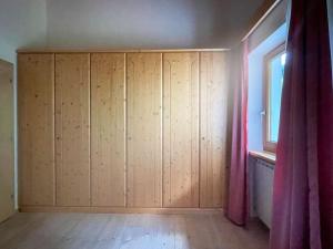 Habitación con armarios de madera y ventana. en Dolomiten View - South Tyrol, en Villandro
