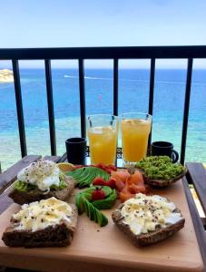 una tabla de cortar con tostadas y zumo de naranja en una mesa en Beach front High End apartment, direct sea views., en Marsalforn