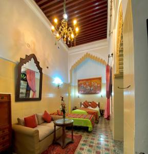 a living room with a couch and a chandelier at Riad Baddi in Salé