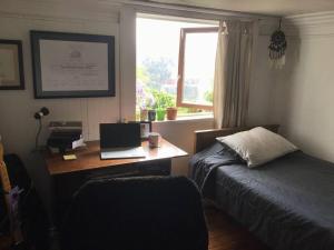 1 dormitorio con escritorio, ordenador portátil y cama en Gran Departamento en Cerro Alegre con única vista al puerto en Valparaíso