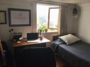 Un dormitorio con un escritorio con una computadora portátil y una cama. en Gran Departamento en Cerro Alegre con única vista al puerto, en Valparaíso