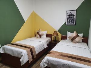 2 camas en una habitación con paredes verdes y amarillas en Tony SaiGon Hotel en Ho Chi Minh