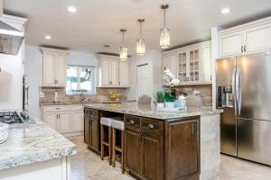 a kitchen with white cabinets and a stainless steel refrigerator at New! Tropical Escape in Pompano with private heated Pool, Spa, and Covered Pergola in Pompano Beach