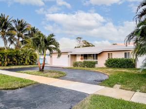 a house with a palm tree and a driveway at New! Tropical Escape in Pompano with private heated Pool, Spa, and Covered Pergola in Pompano Beach
