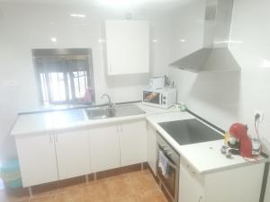 cocina blanca con fregadero y microondas en casa luna cuesta del rio 15, en Valdeganga