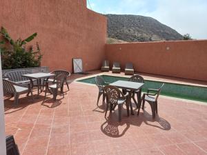 un patio con mesas y sillas junto a una piscina en La bananeraie, en Tamri