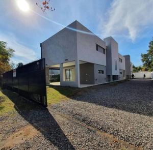 ein großes weißes Haus mit einem Zaun davor in der Unterkunft Duplex de Categoria - con estacionamiento gratuito in Cordoba