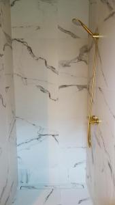a shower with white marble walls and a gold shower head at Domek Dzikie Lisko in Lesko
