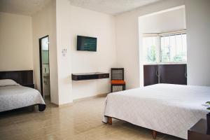 sypialnia z 2 łóżkami i telewizorem na ścianie w obiekcie Hotel Cupules w mieście Mérida