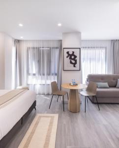 a bedroom with a bed and a couch and a table at Jerusalén Suites Alicante in Alicante