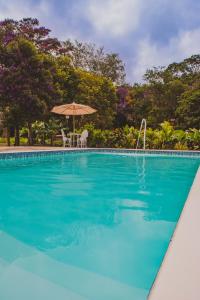 a swimming pool with two chairs and an umbrella at Villaflor Pousada in Vale do Capao