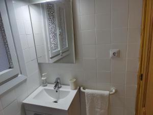 a white bathroom with a sink and a mirror at Ático Carrasco in Benidorm