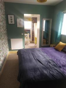 a bedroom with a purple bed and a mirror at Cosy Wellbeing Stays on Cornish Coast in Falmouth