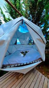 a bed in a tent on a deck at Glamping El Edén Guasca Cundinamarca in Guasca