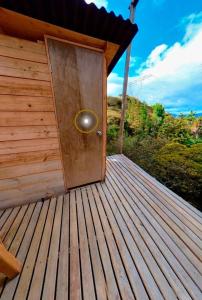 una puerta de madera en una terraza de madera con una colina en Glamping El Edén Guasca Cundinamarca en Guasca