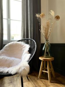 une chaise noire avec un oreiller blanc et un vase fleuri dans l'établissement Bel appartement proche gare, centre ville d'Angers, à Angers