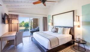 a bedroom with a bed and a table and a desk at Wyndham Tortola BVI Lambert Beach Resort in East End
