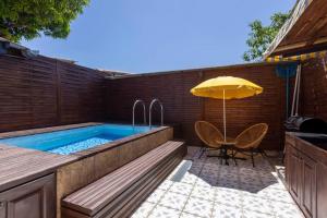 uma piscina com um guarda-sol, uma mesa e uma cadeira em Villa Comfort-Soleil em Kourou