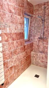 uma casa de banho com um chuveiro e uma parede de tijolos em Maison de village em Fontvieille