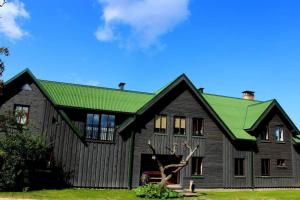 duży drewniany dom z zielonym dachem w obiekcie Viesu māja Zvilnis w mieście Pāvilosta