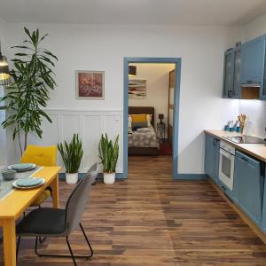 uma cozinha e sala de jantar com armários azuis e uma mesa em Jégmadár Apartman em Debrecen