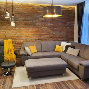 a living room with a couch and a brick wall at Jégmadár Apartman in Debrecen